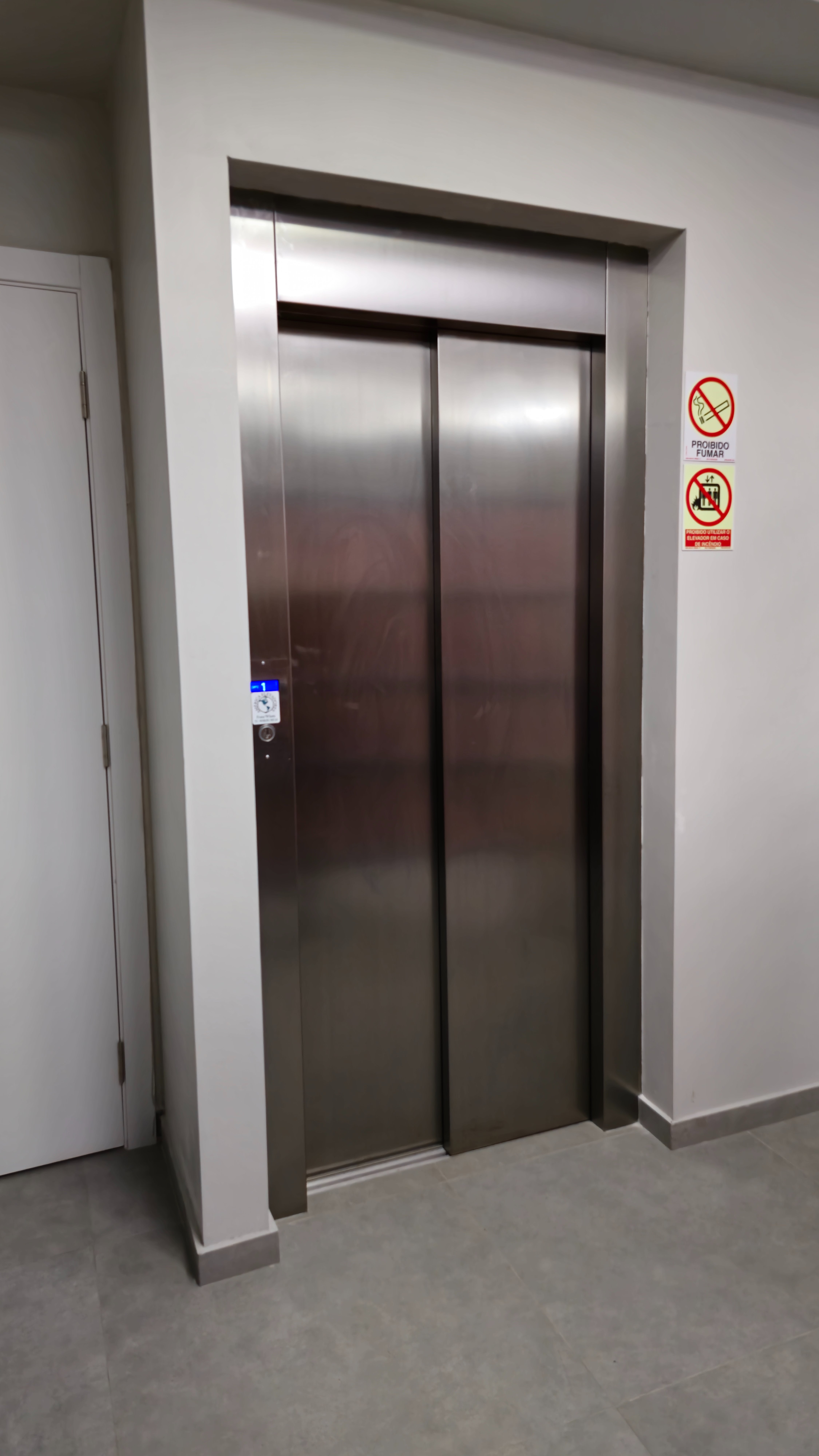 Porta de elevador em inox em corredor residencial